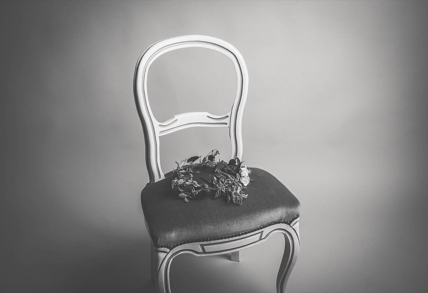 A painted antique balloon-back chair with a sprig of dried flowers on the seat